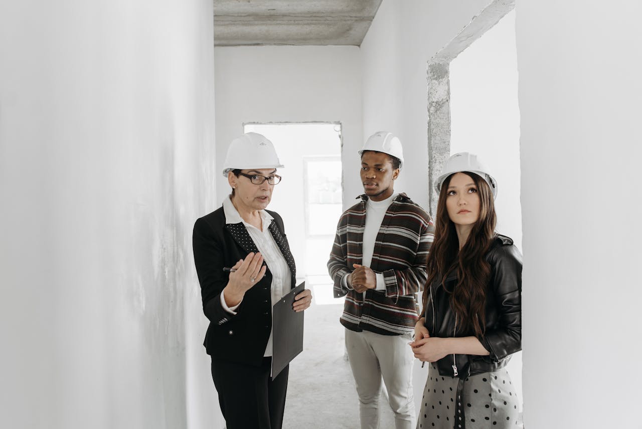 Real Estate Agent and Young Couple in Helmets having Conversation